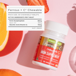 Iron supplement bottle with nutritional information on a pink background with fruits.